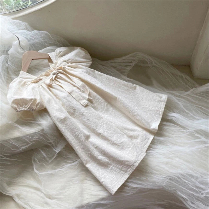 White dress with sheer overlay on a hanger against a neutral background